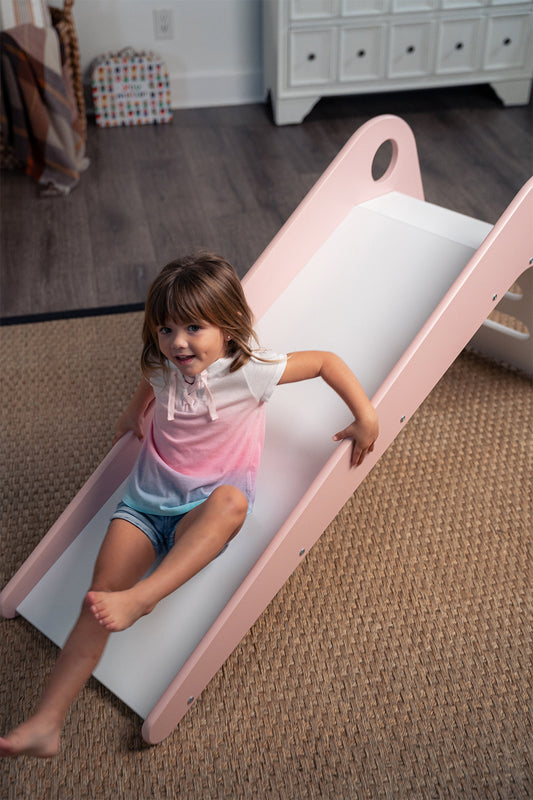 Girl Sliding Down Manuka - Avenlur's Safe and Fun Indoor Toddler Slide in Playroom. Shown in Pink.