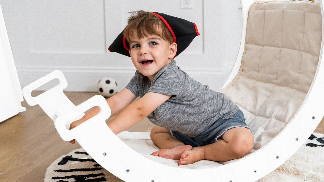 Toddler playing on the Avenlur Hazel wooden Pikler triangle set in a bright playroom