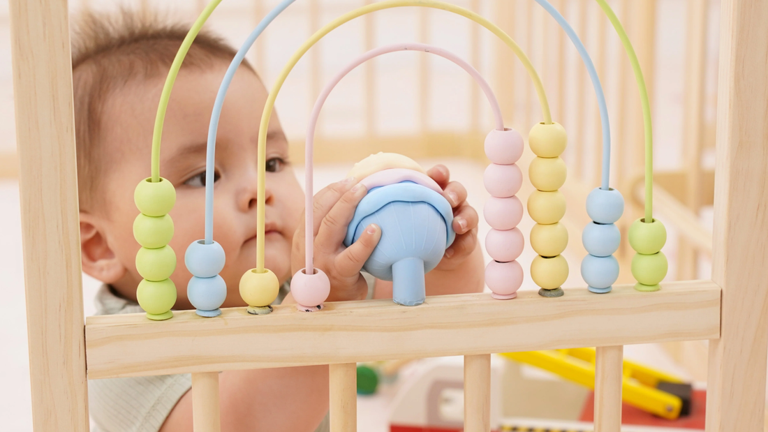 Close-up of the Montessori activity panel with geometric blocks and tactile ribbons on the Avenlur wooden playpen