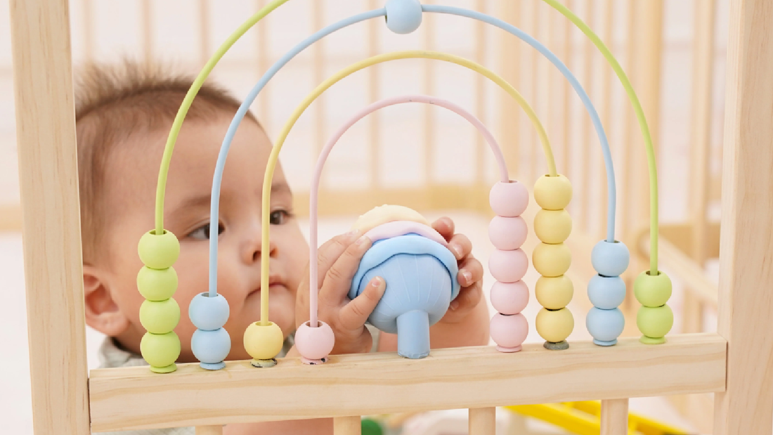 Close-up of the Montessori activity panel with geometric blocks and tactile ribbons on an Avenlur wooden playpen
