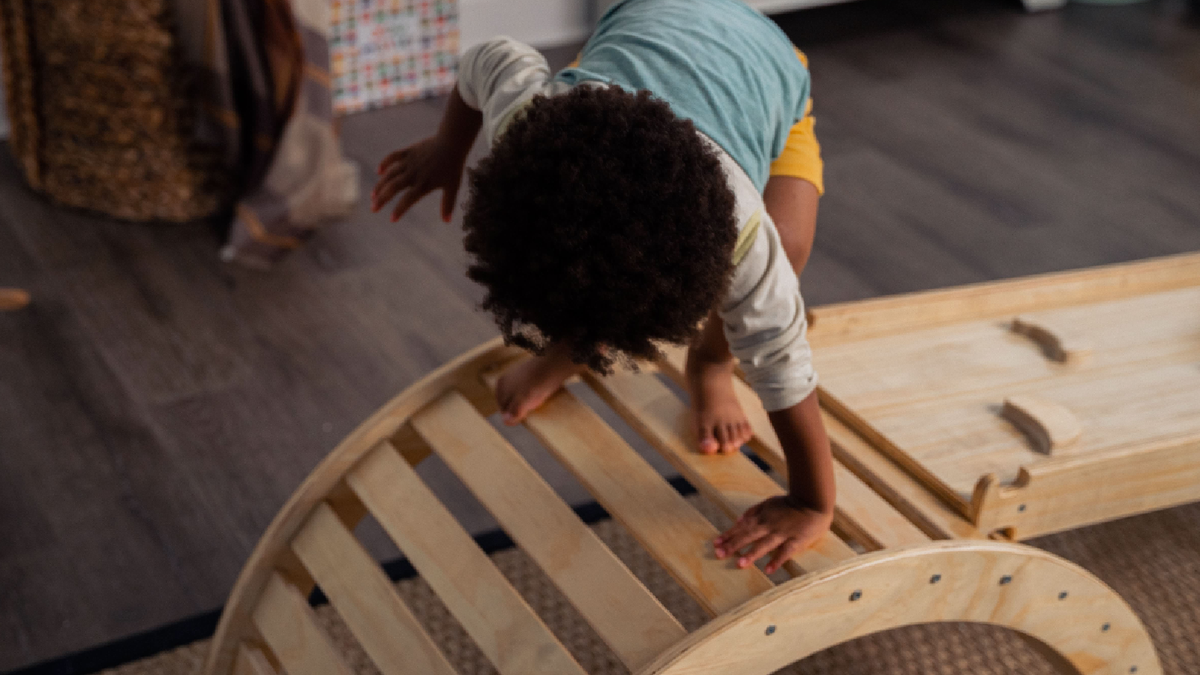 Toddler playing on an Avenlur wooden Montessori climbing set