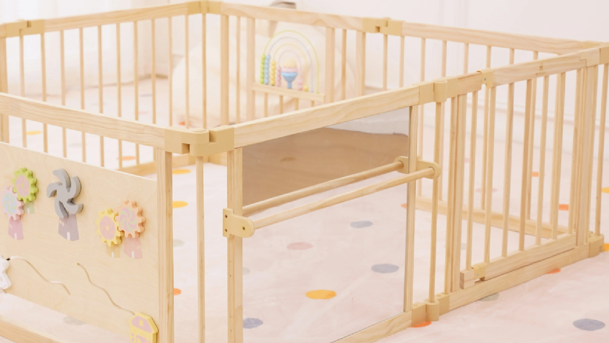 Baby playing inside an Avenlur wooden playpen with mirror and activity panels