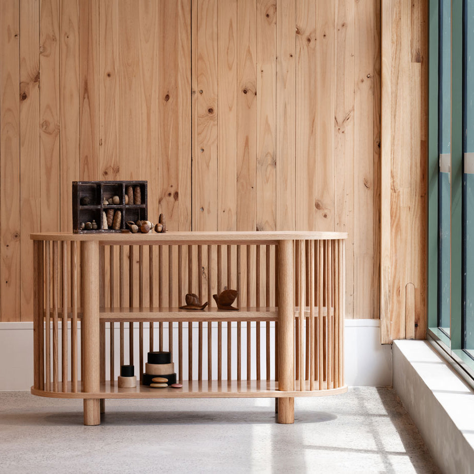 Wooden console table against a wooden wall with a window in the background