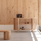 Wooden cabinet against a wooden paneled wall with a bench in front
