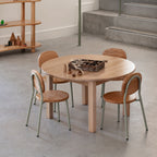 Round wooden table with four chairs in a modern interior setting.