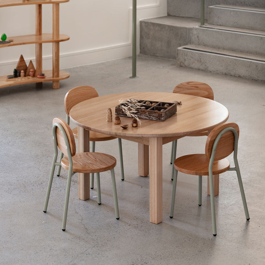 Round wooden table with four chairs in a modern interior setting.