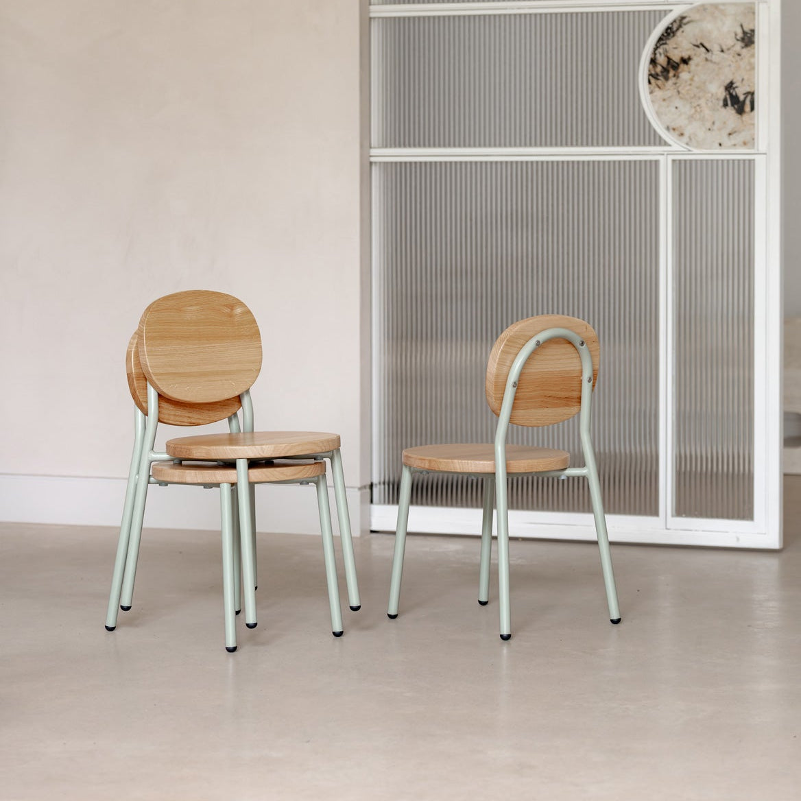 Two wooden chairs with metal legs in a minimalistic room.