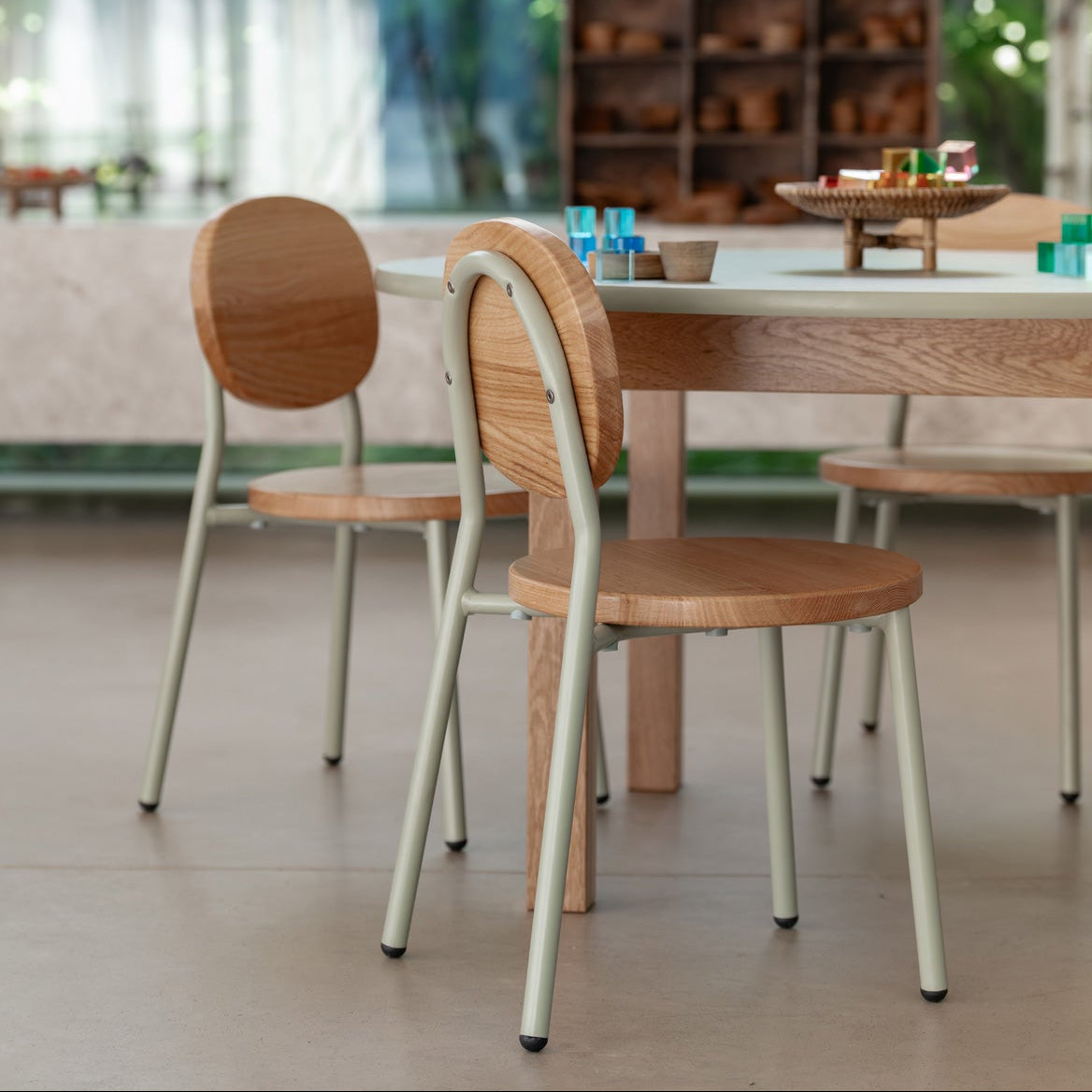 Dining area with wooden chairs and a table, blurred greenery in the background