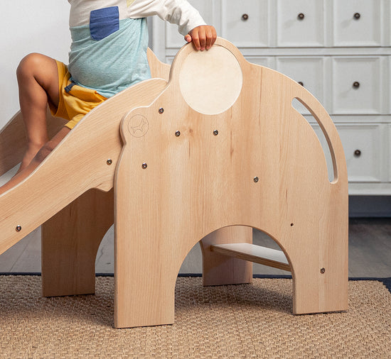 Child Sitting on Nima - Avenlur's Elephant Slide in Natural Wood Color - Side View in Detail