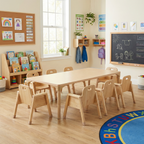 Children's classroom with wooden table and chairs, books, and educational materials.