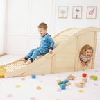 Children playing on a wooden slide in a room with toys scattered around.
