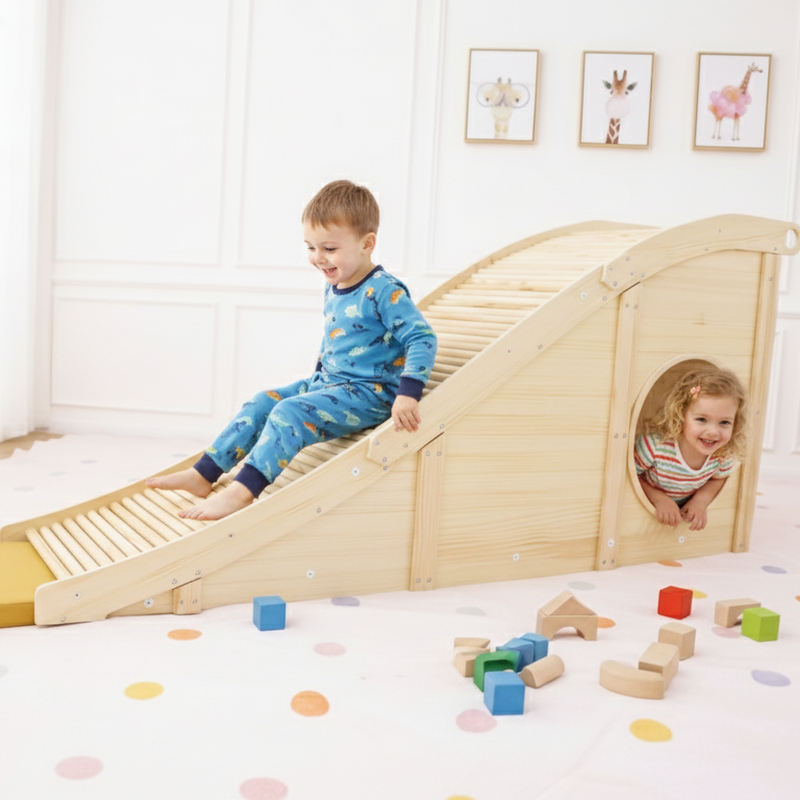 Children playing on a wooden slide in a room with toys scattered around.