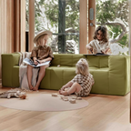 Children playing in a modern living room with a green sofa.