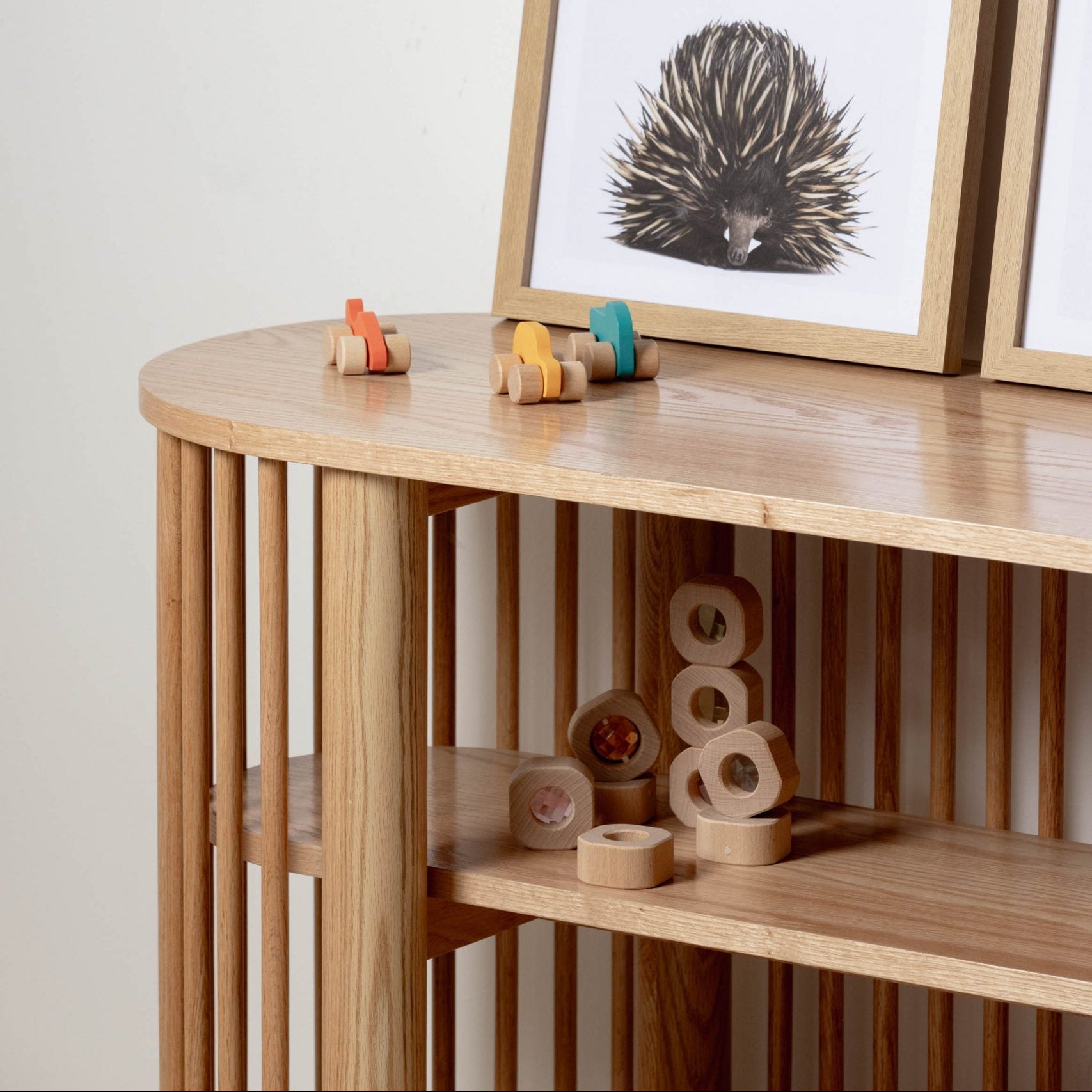 Wooden shelf with toys and framed artwork on a white wall