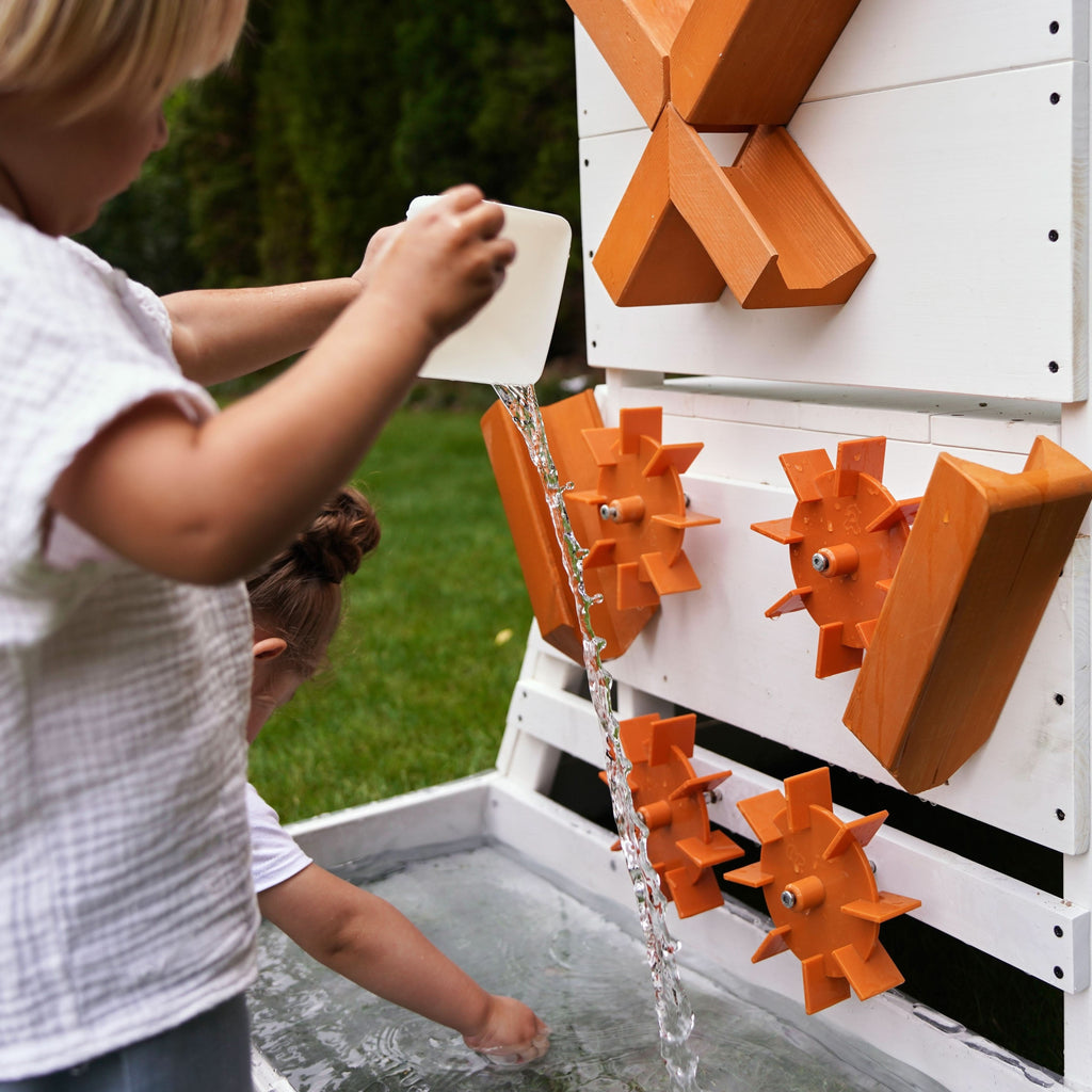 Child pouring water through the Aloe playhouse sensory water wheel activity panel