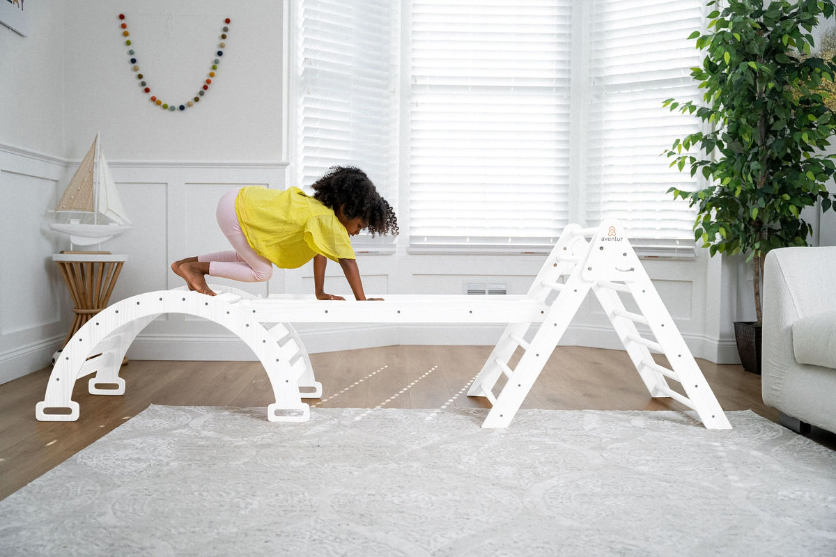 Toddler reaching the top of the Avenlur Hazel Pikler triangle
