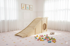 Toddler sliding down the Avenlur Hickory indoor slide