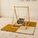 Baby swinging in the Avenlur Spruce swing over the cushioned Spruce play mat