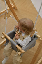 Toddler in the Avenlur Spruce gray indoor toddler swing