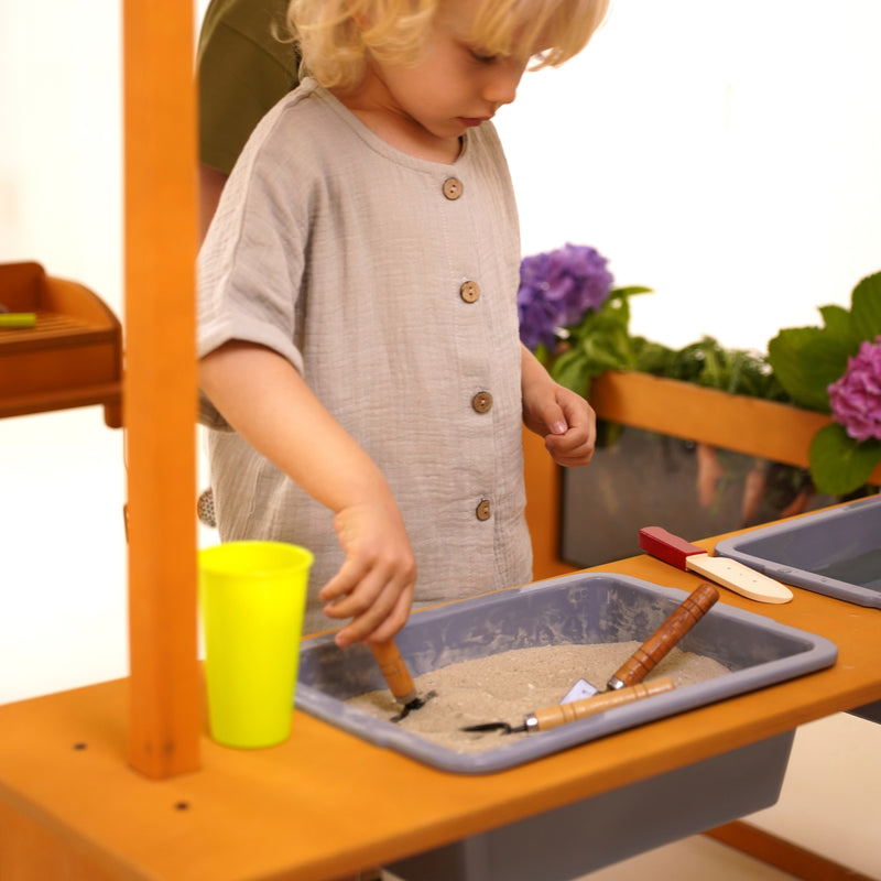 Young child playing with sand in sensory bin of the Avenlur Sumac mud kitchen