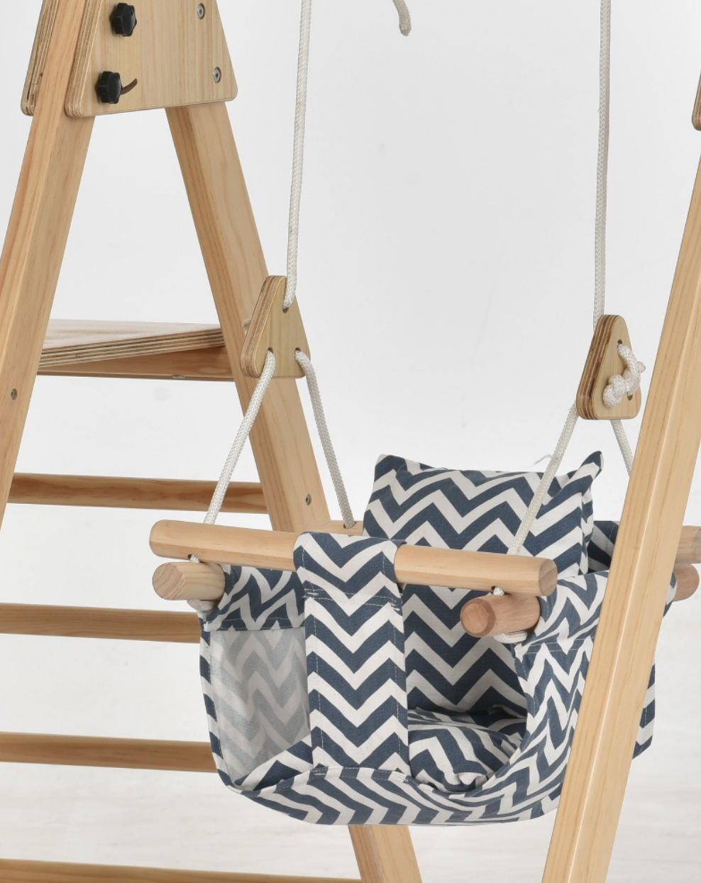 Avenlur cotton canvas baby swing seat in a navy and white chevron pattern with wooden front bar, hanging from a wooden climber