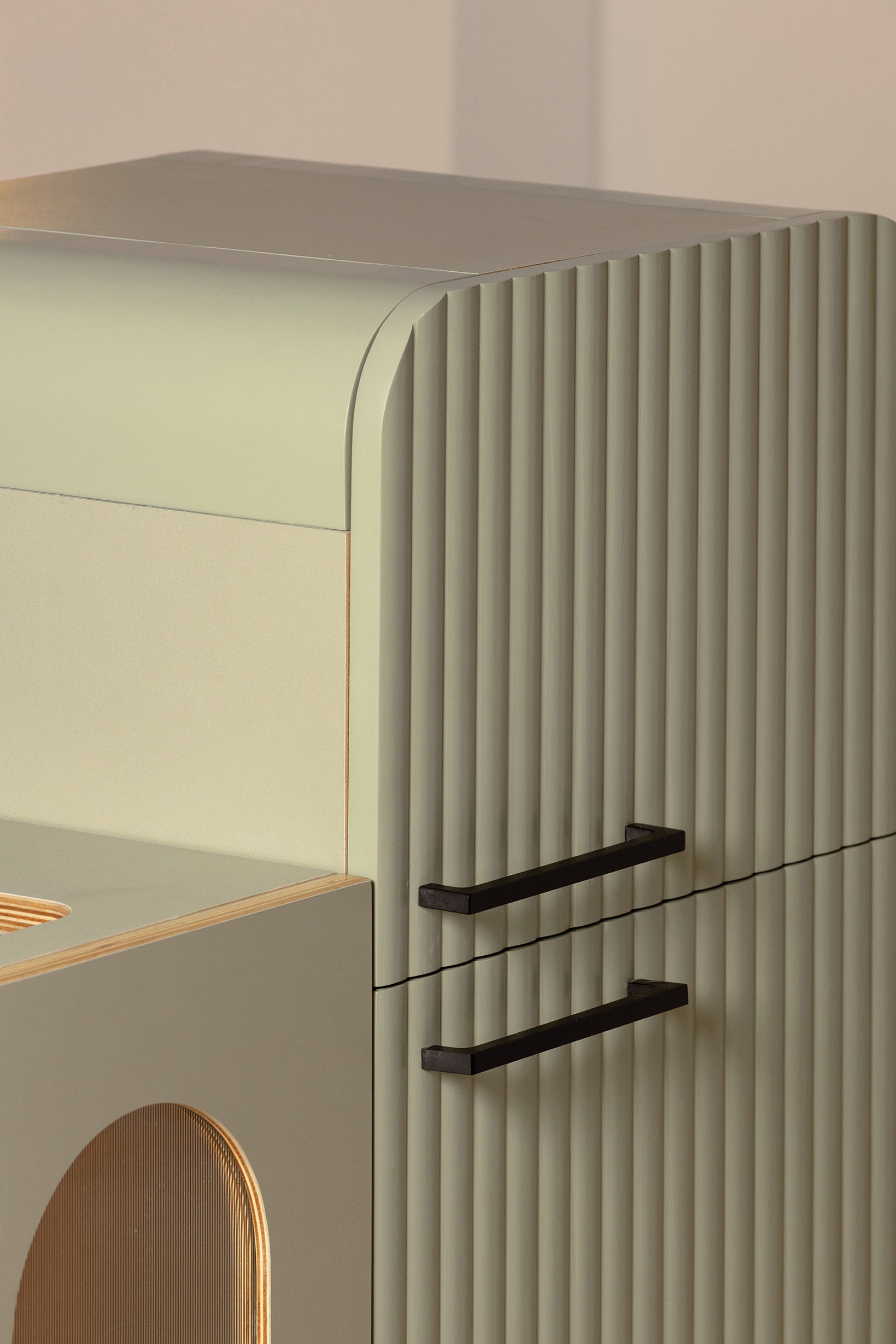 Close-up of the sage green fluted fridge with rounded top and matte black handles