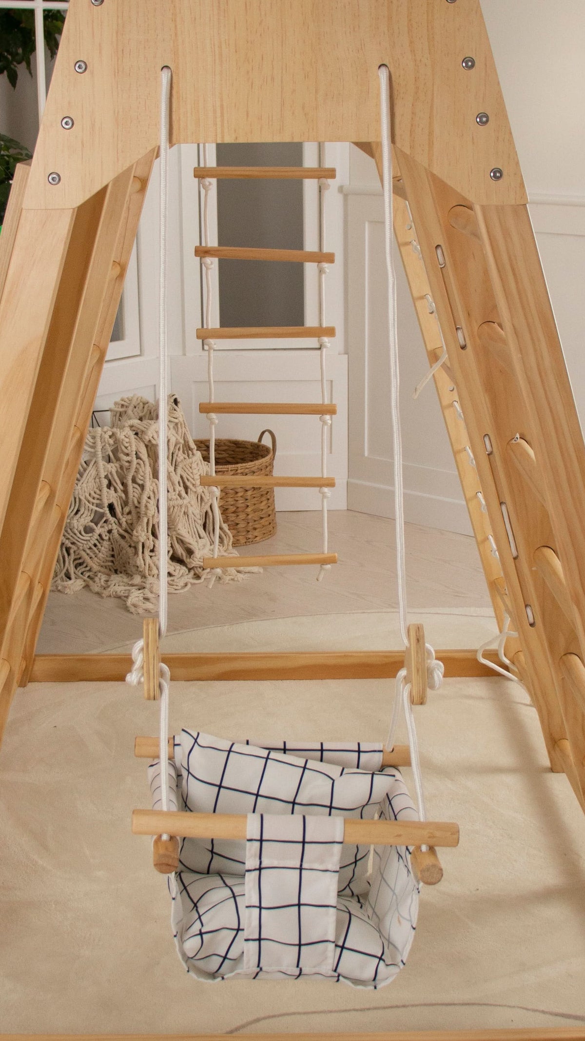 Avenlur indoor baby swing seat hanging from a wooden indoor climbing frame in a playroom