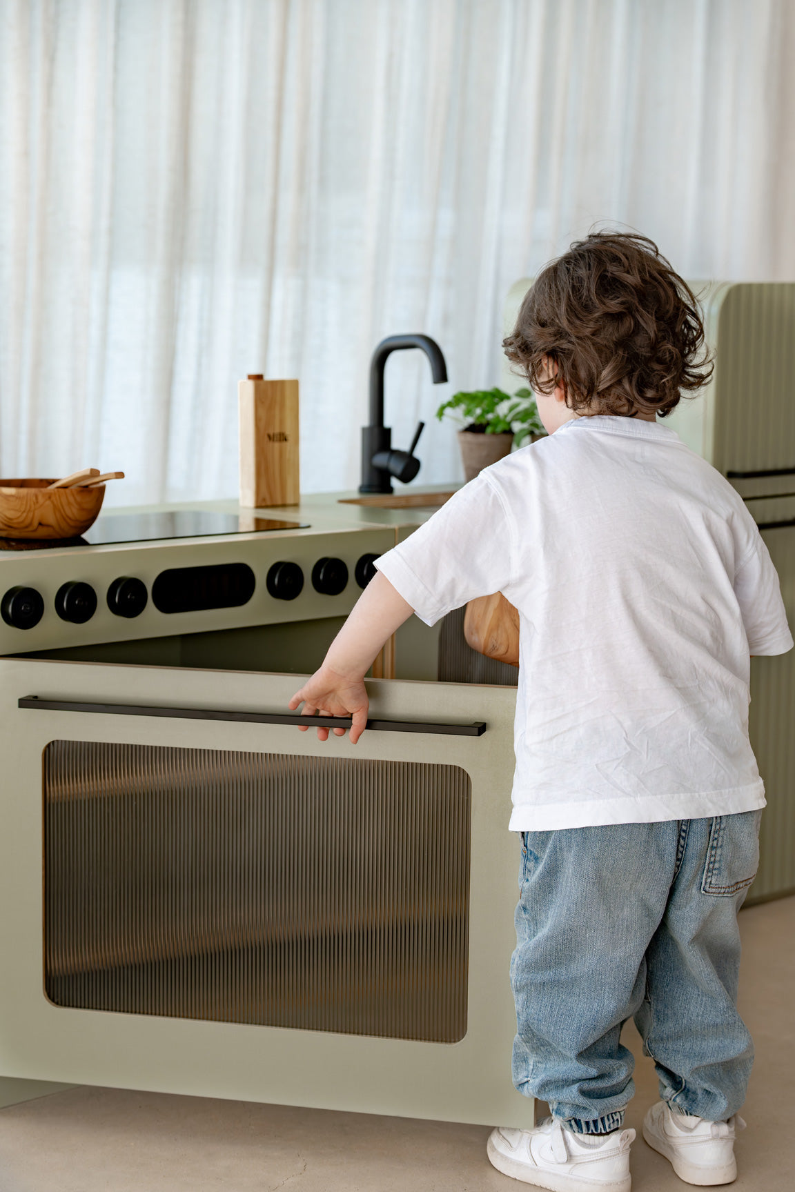 Child opening the door of the sage green Sage Fluted play oven