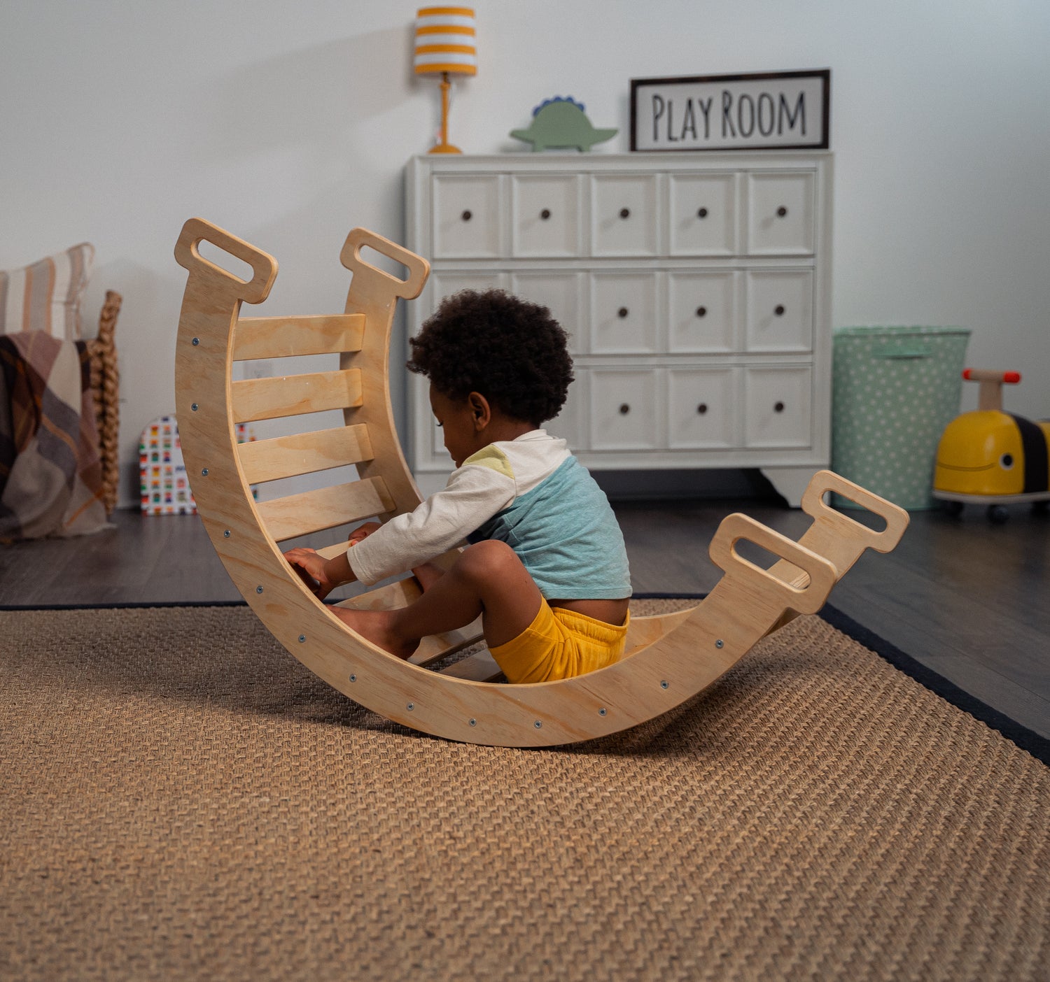Child rocking on Hazel - Avenlur's Pikler Triangle Ladder with Arch Ramp, Slide, Rocker, and Triangle Rock Climber