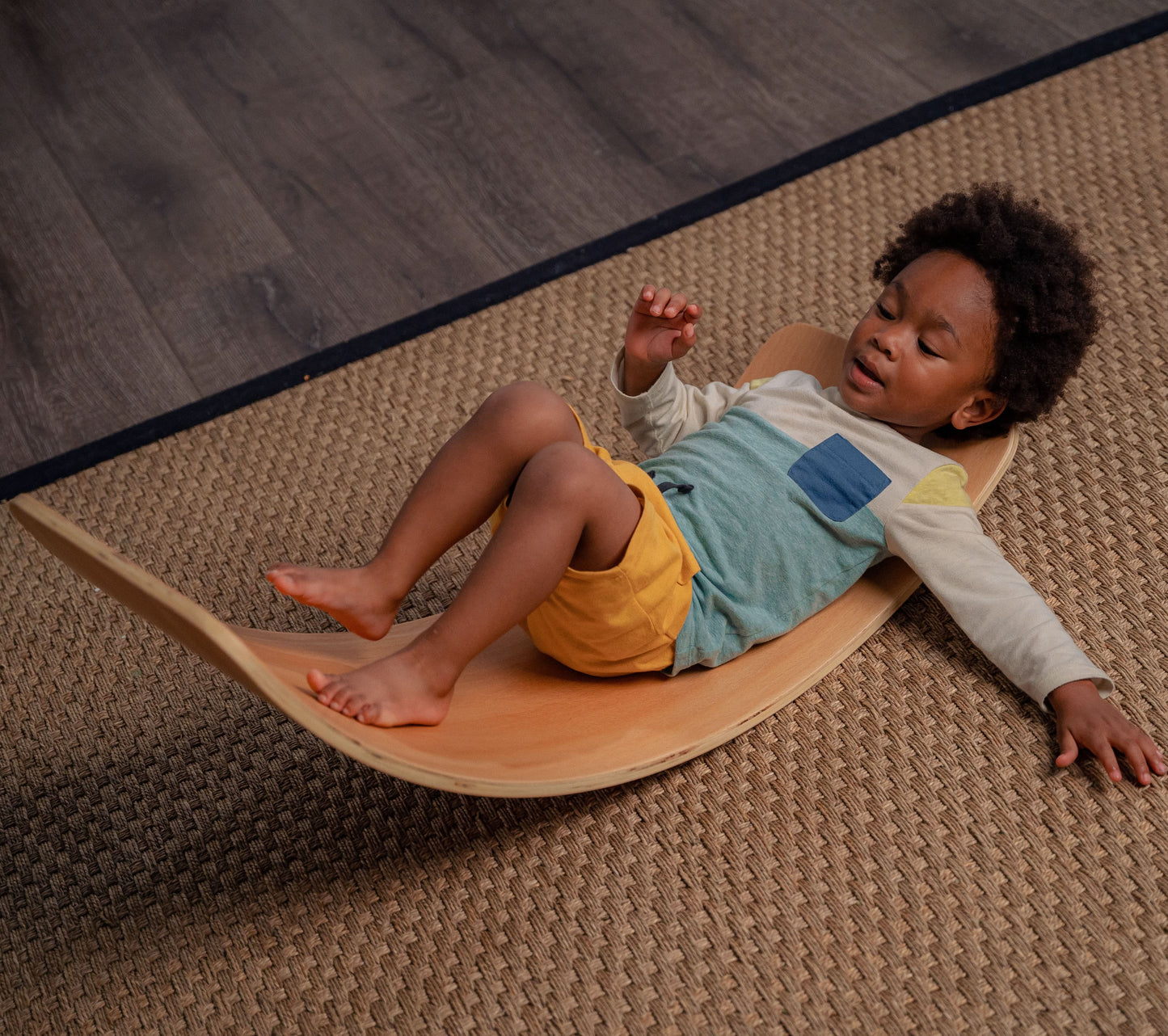 Toddler Laying on Redbud - Avenlur's Curvy Rocker Wobble Balance Board for Yoga & Exercise