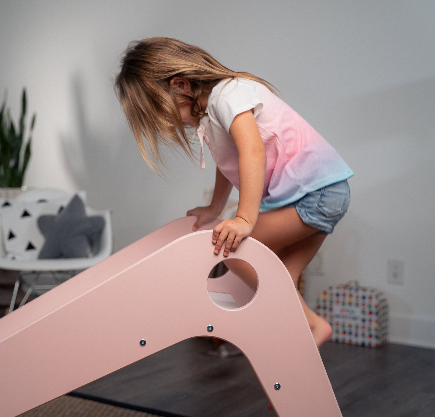 Girl Climbing Up Manuka - Avenlur's Safe and Fun Indoor Toddler Slide in Playroom. Shown in Pink.
