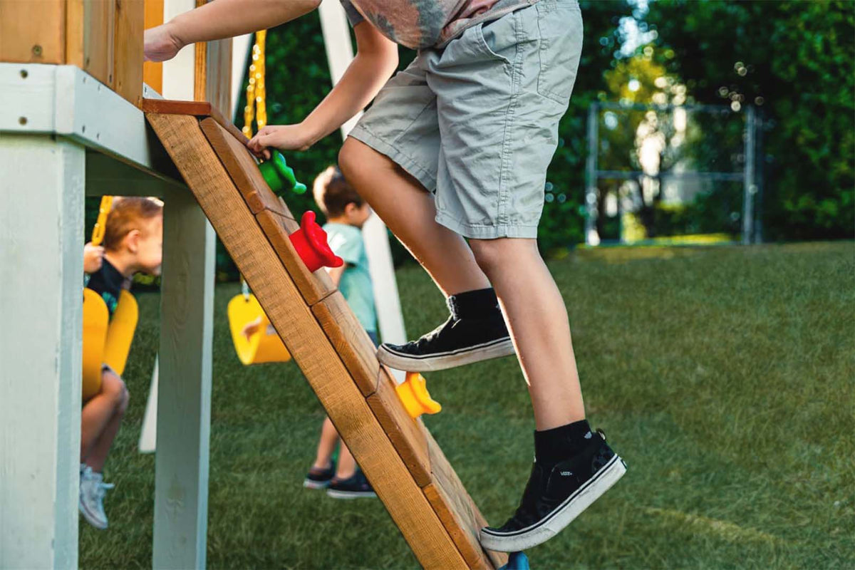 Side view of the Avenlur Forest swing set rock wall
