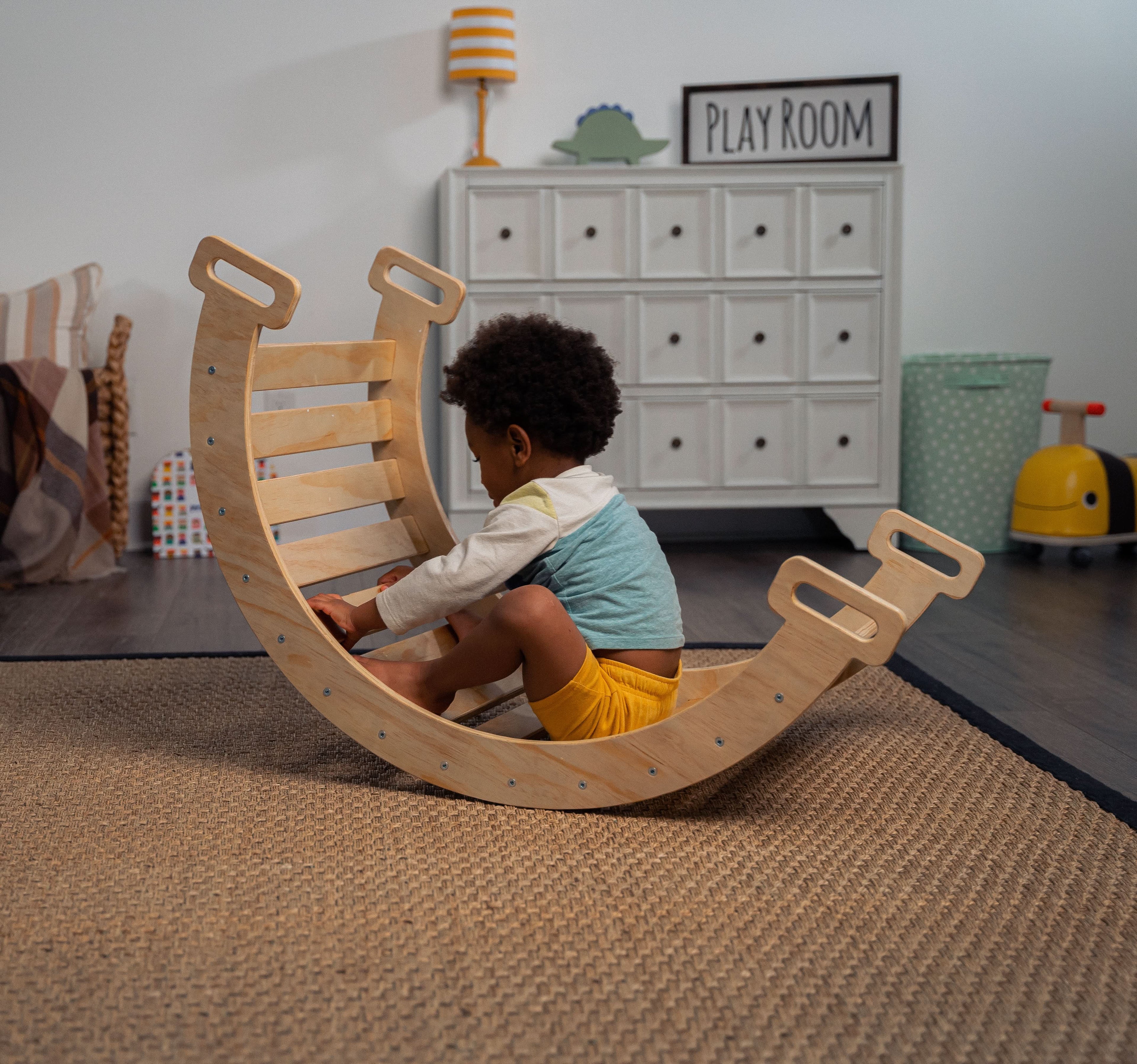 Child sitting inside Avenlur Hazel Pikler Rocking Arch in cozy playroom setting