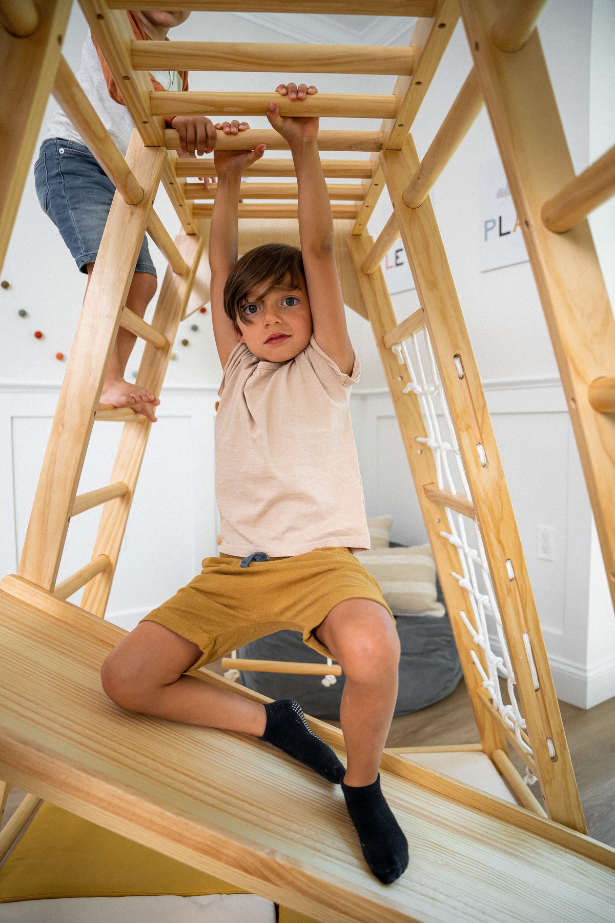 Avenlur Magnolia indoor wooden jungle gym with climbing wall, slide and monkey bars set up in a bright playroom