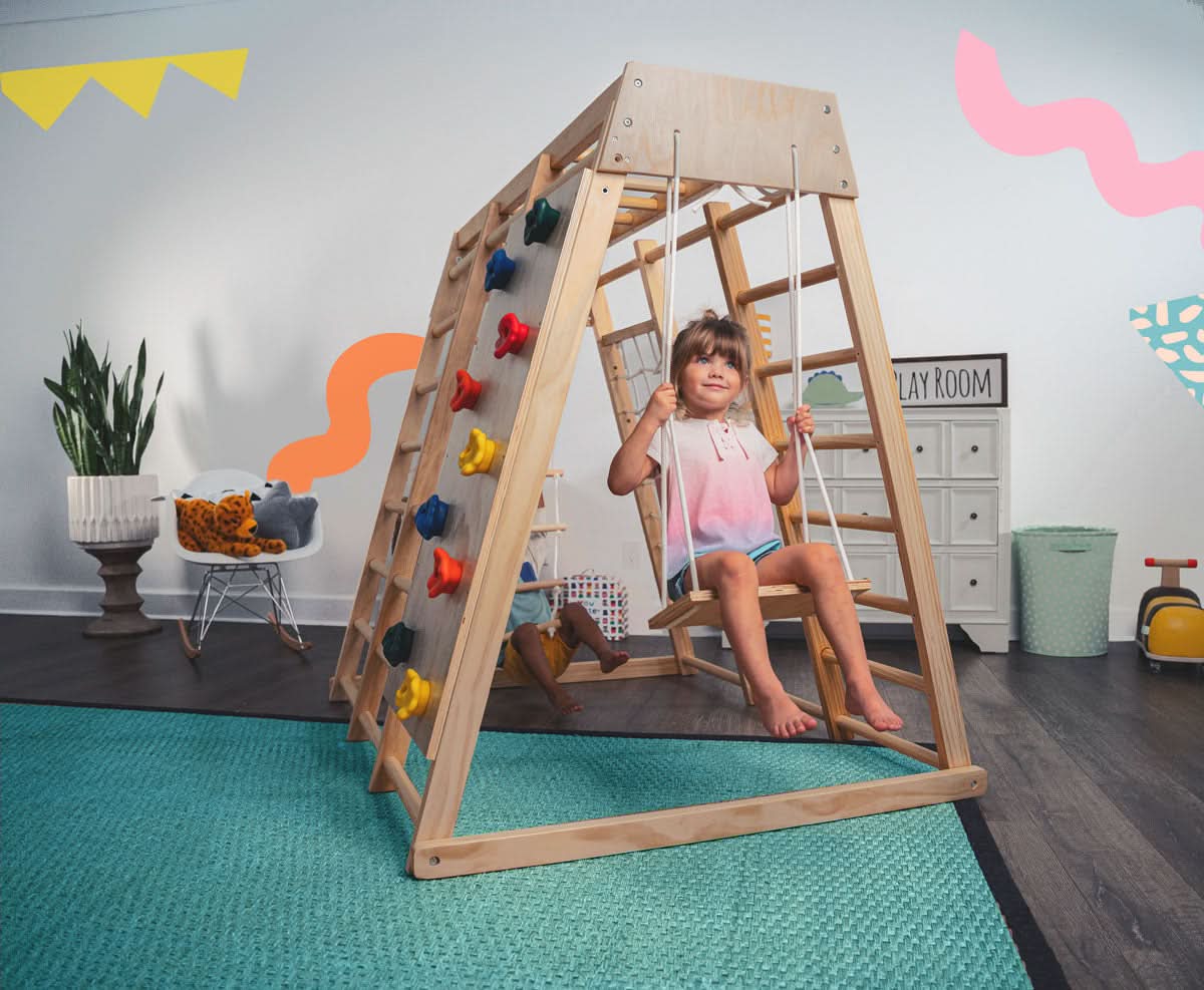 Avenlur Magnolia indoor wooden jungle gym in rainbow color finish with monkey bars, rock wall and slide