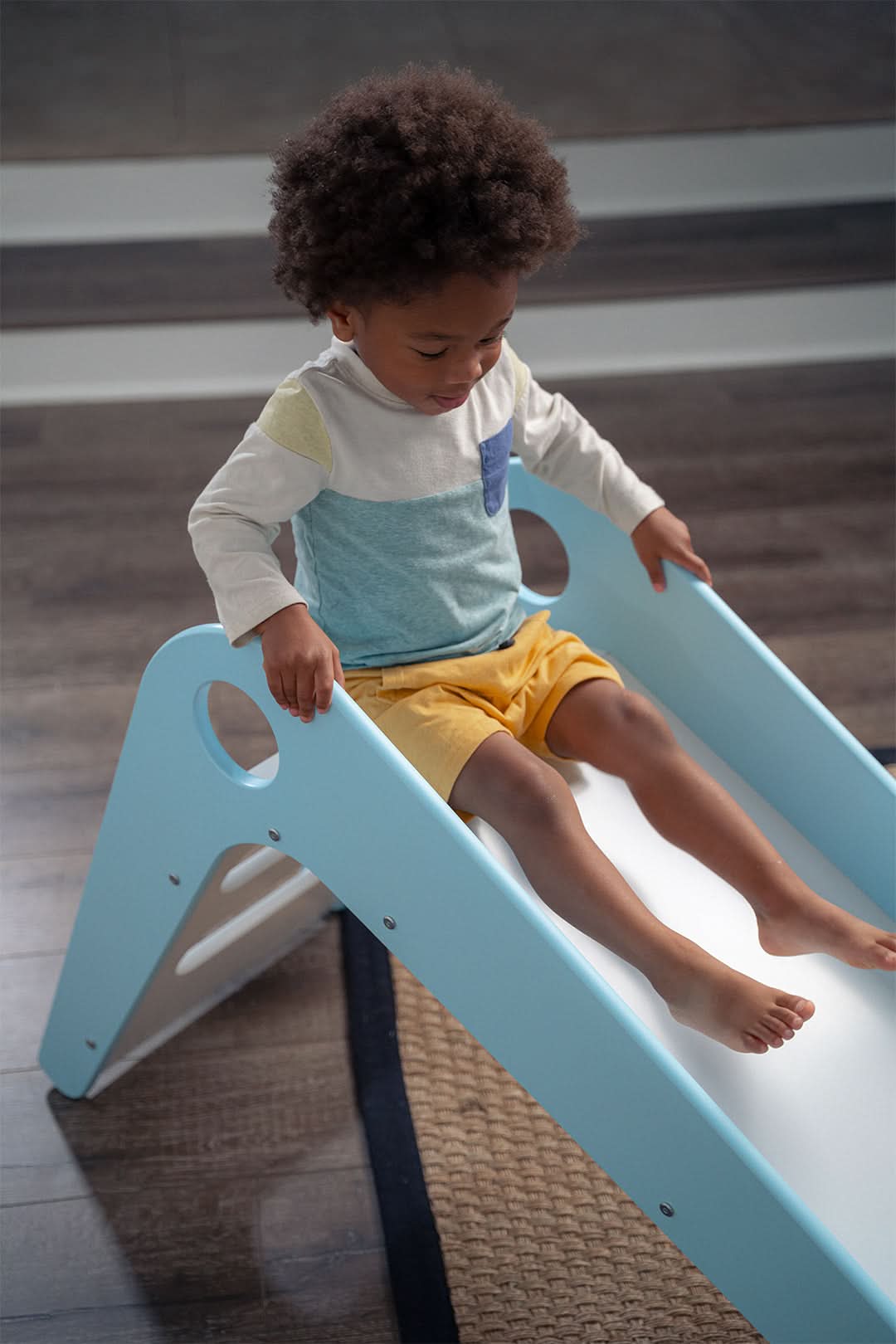 Young child sliding on the Avenlur Manuka baby slide at home