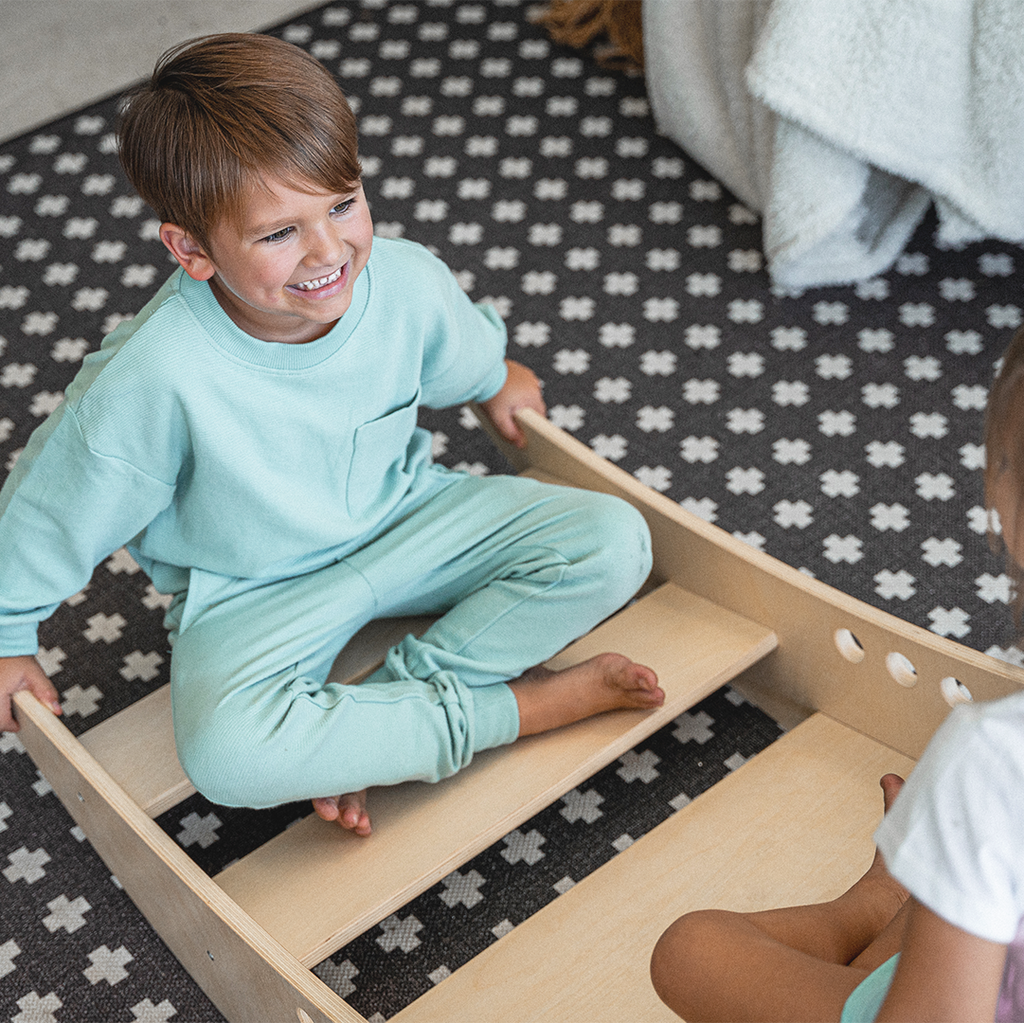Smiling toddlers rocking together in the Avenlur Rowan wooden rocking boat