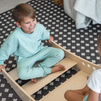 Smiling toddlers rocking together in the Avenlur Rowan wooden rocking boat